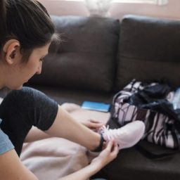woman with hearing aid putting on running shoes