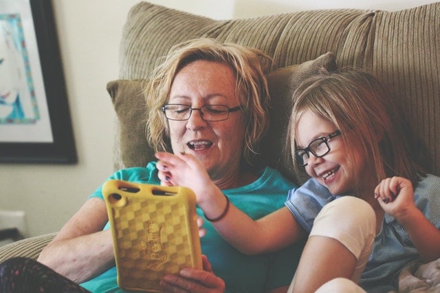 truth about hearing loss woman and young girl sitting in a recliner while playing with a tablet