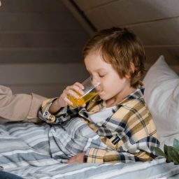Mother giving her young son juice to help him feel better.