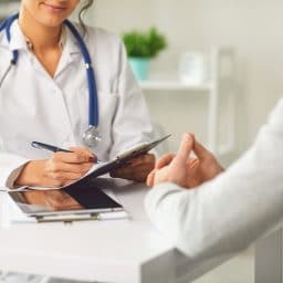 A doctor speaks with a patient inside of a medical office setting.