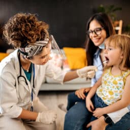 Young girl at the doctor with her mom getting her tonsils checked.