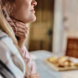 Woman with sore throat holds neck