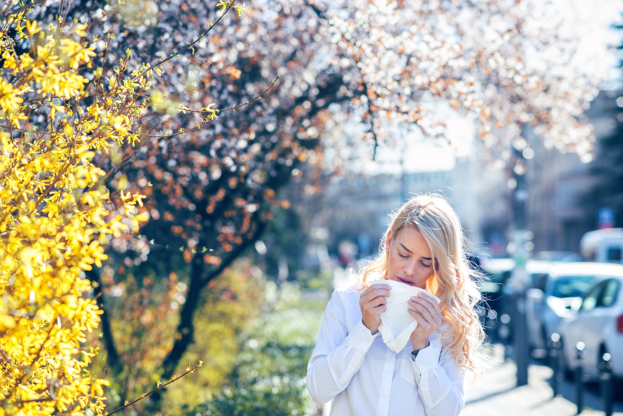 Woman sneezes near trees