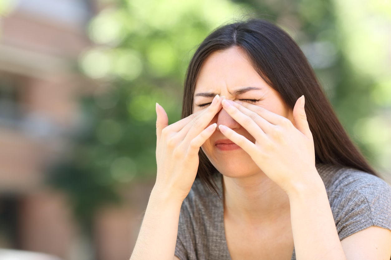 Woman scratching itchy eyes in the street.