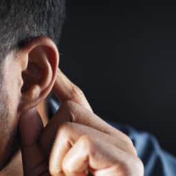 Man with swollen lymph node touches behind his ear.