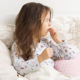 Child with allergies coughing in bed.