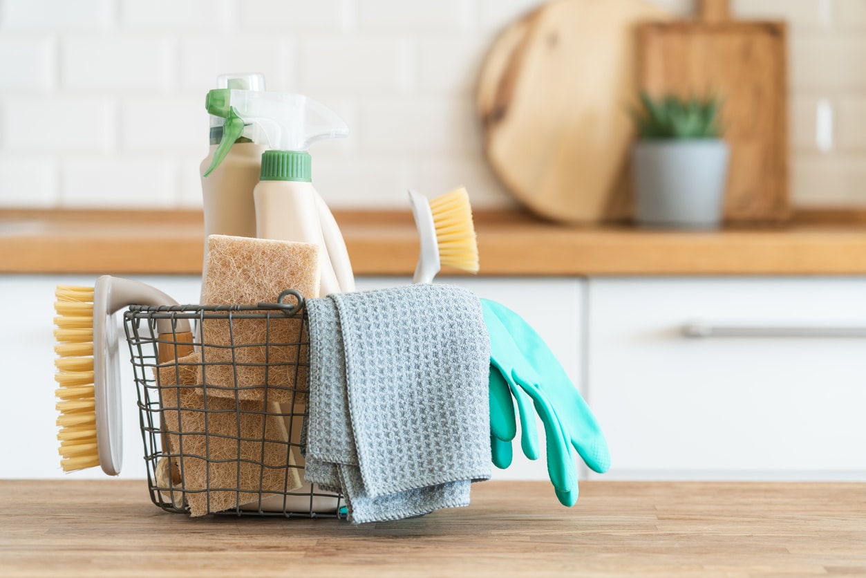 Basket of cleaning supplies: gloves, towels, rags, brushes, cleaning spray