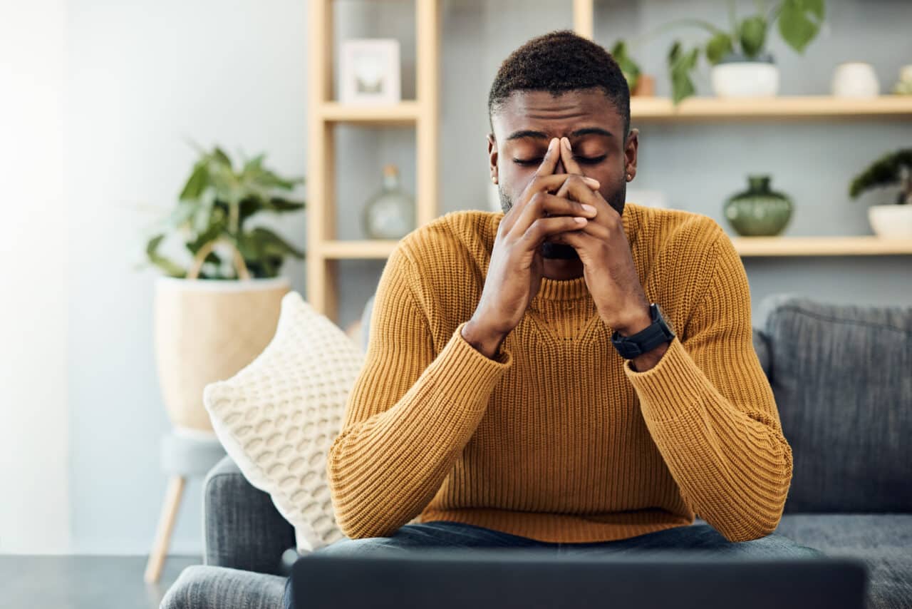 Stressed man at home in his living room looking worried.
