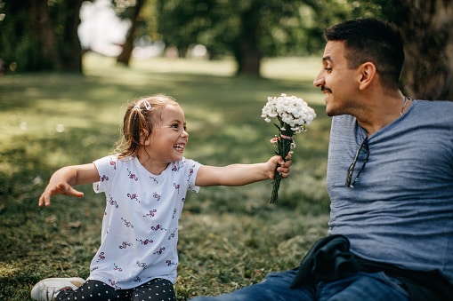 Man with allergies is sniffle-free thanks to sublingual immunotherapy as his daughter hands him a spring bouquet of flowers.