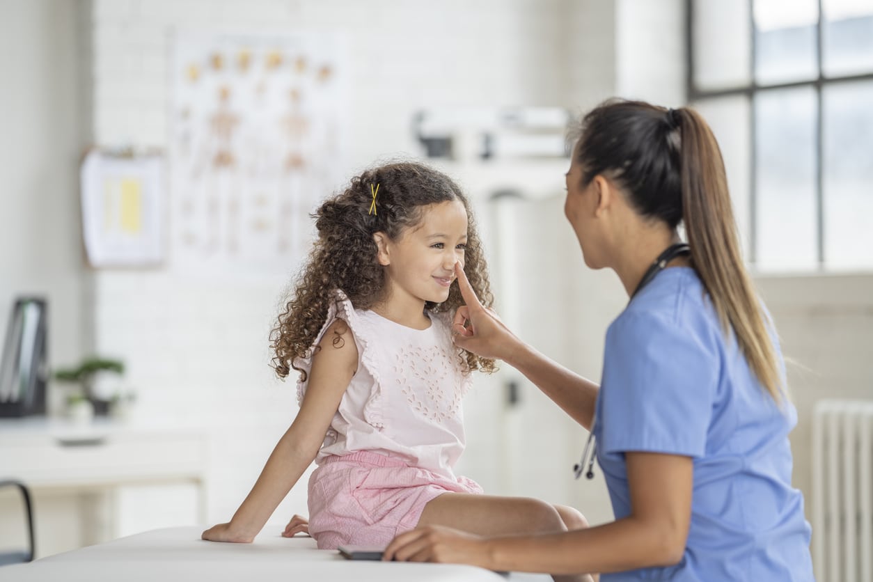Allergist teases her pediatric patient by touching her nose after administering a dose of allergen immunotherapy to treat the child's allergies.